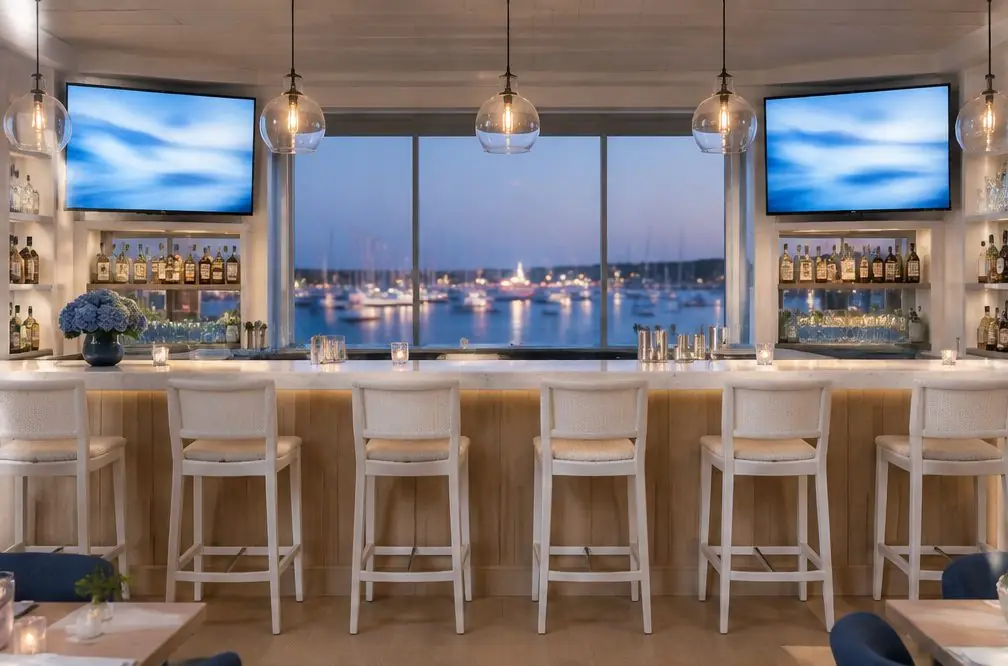 Illustration: two TVs mounted at matched heights above a long bar with white stools, glass pendant lights and a window to a harbor at dusk